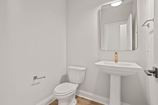 bathroom featuring toilet, a sink, baseboards, and wood finished floors