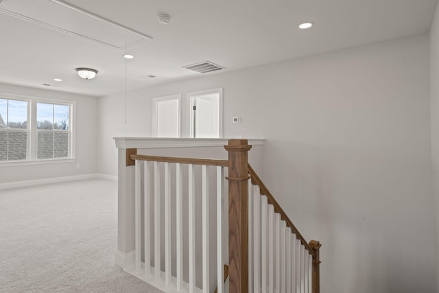 hall featuring carpet, visible vents, attic access, an upstairs landing, and baseboards