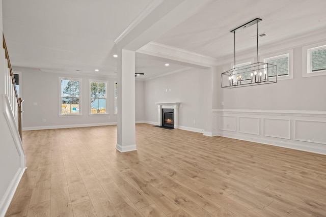 unfurnished living room with visible vents, stairway, a fireplace with flush hearth, ornamental molding, and light wood-type flooring