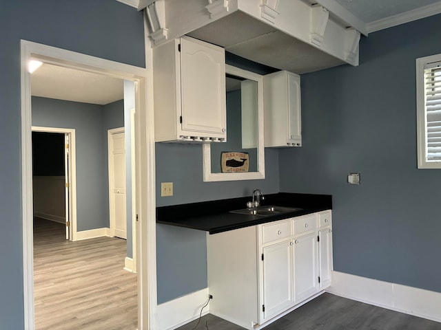 kitchen with light hardwood / wood-style flooring, white cabinetry, crown molding, and sink