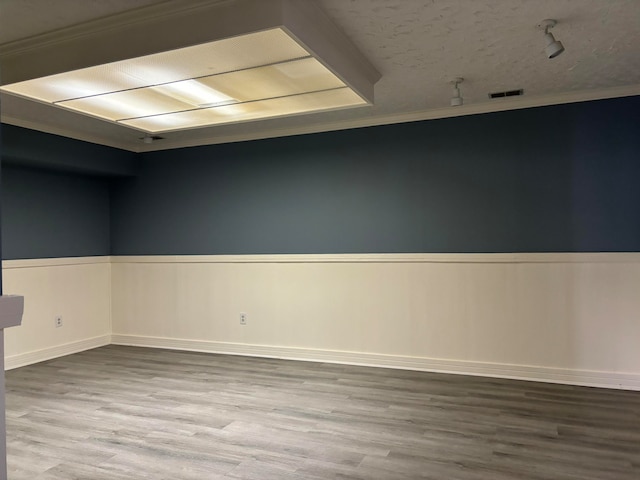 spare room with hardwood / wood-style floors, crown molding, and a textured ceiling