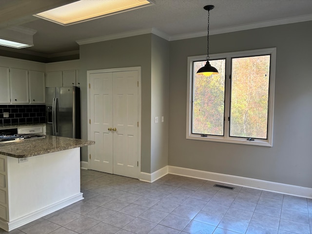 kitchen with dark stone counters, crown molding, light tile patterned floors, decorative light fixtures, and stainless steel fridge with ice dispenser