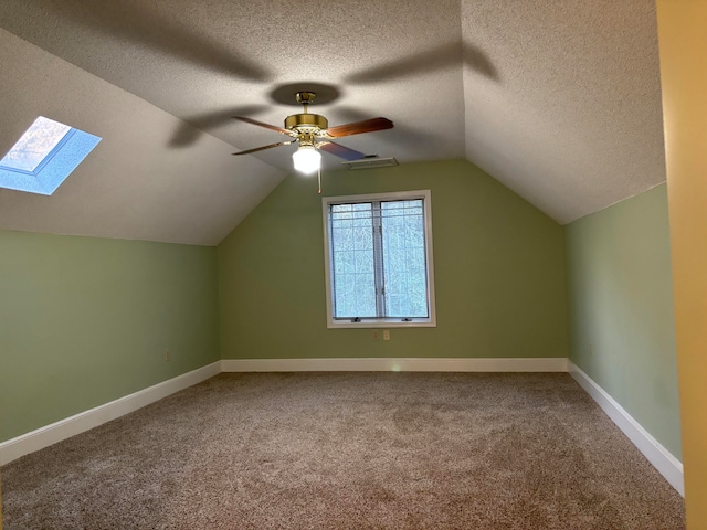 bonus room with carpet flooring, a textured ceiling, lofted ceiling with skylight, and ceiling fan