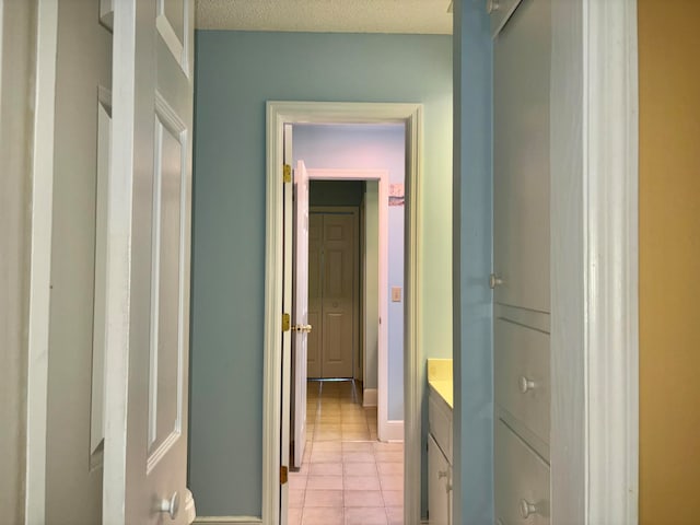 corridor featuring light tile patterned floors and a textured ceiling