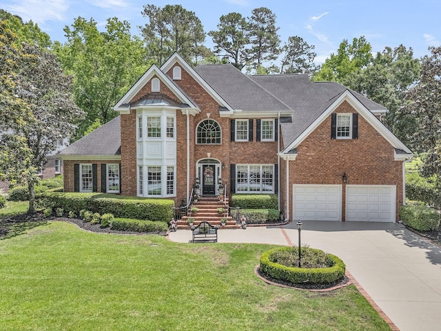 8662 W Fairway Woods Dr, North Charleston, SC 29420 - georgian-style home featuring brick siding, concrete driveway, a front lawn, a garage, and a shingled roof