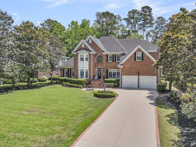 8662 W Fairway Woods Dr, North Charleston, SC 29420 - colonial-style house with brick siding, concrete driveway, an attached garage, and a front yard