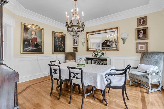 8662 W Fairway Woods Dr, North Charleston, SC 29420 - dining space with a chandelier, light wood finished floors, ornamental molding, a wainscoted wall, and a decorative wall