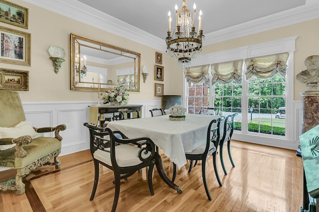 8662 W Fairway Woods Dr, North Charleston, SC 29420 - dining space with a chandelier, a wainscoted wall, crown molding, a decorative wall, and light wood-style flooring