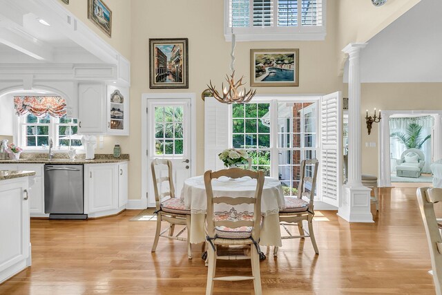 8662 W Fairway Woods Dr, North Charleston, SC 29420 - dining area with plenty of natural light, a towering ceiling, light wood-style flooring, and ornate columns