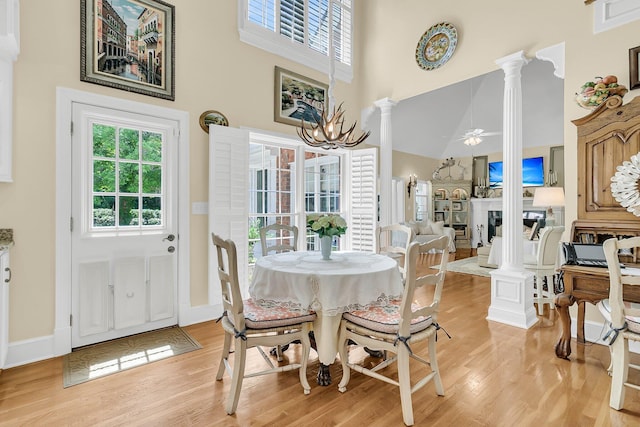 8662 W Fairway Woods Dr, North Charleston, SC 29420 - dining space featuring a high ceiling, light wood-style flooring, decorative columns, ceiling fan, and a chandelier