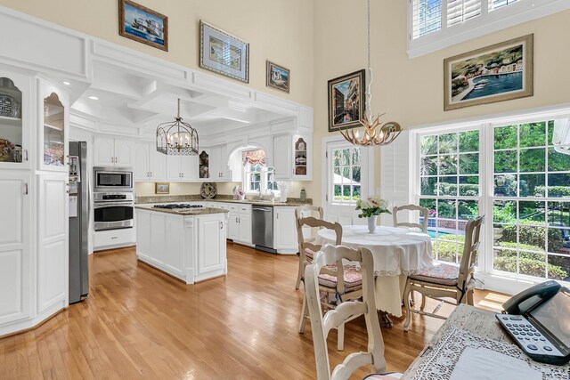 8662 W Fairway Woods Dr, North Charleston, SC 29420 - kitchen with a chandelier, stainless steel appliances, white cabinetry, light wood-style floors, and coffered ceiling