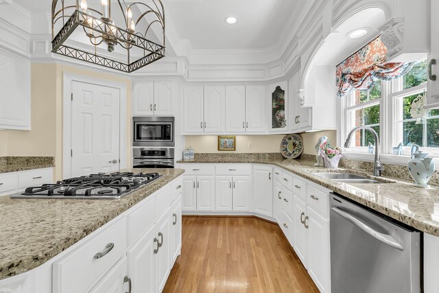 8662 W Fairway Woods Dr, North Charleston, SC 29420 - kitchen featuring appliances with stainless steel finishes, a sink, crown molding, light wood-style floors, and white cabinets