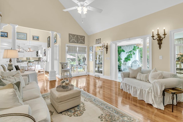 8662 W Fairway Woods Dr, North Charleston, SC 29420 - living room with high vaulted ceiling, decorative columns, a ceiling fan, light wood-type flooring, and a chandelier