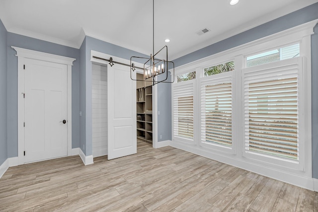 unfurnished dining area featuring visible vents, a healthy amount of sunlight, light wood-type flooring, and an inviting chandelier