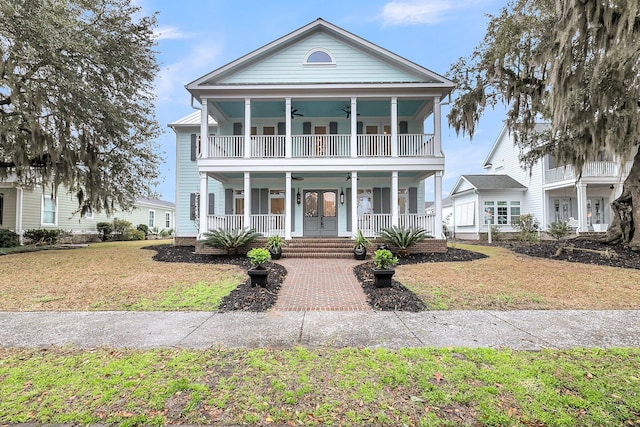 greek revival inspired property featuring a front yard, a porch, a balcony, and a ceiling fan