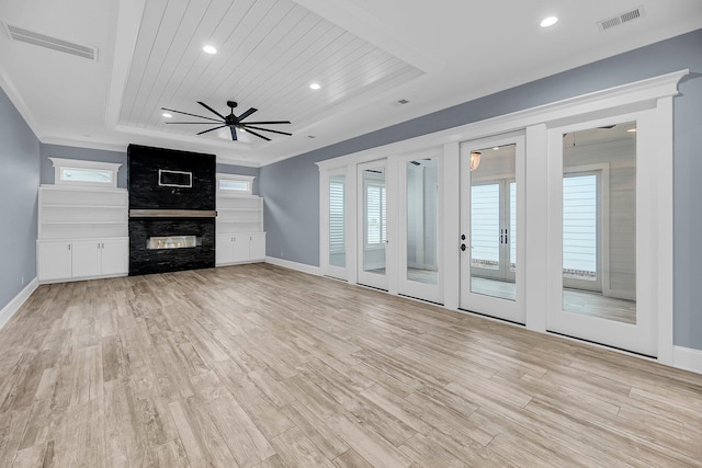 unfurnished living room with a multi sided fireplace, visible vents, a wealth of natural light, and a tray ceiling