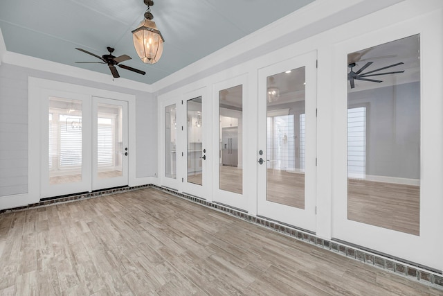 unfurnished sunroom with french doors, a raised ceiling, and ceiling fan