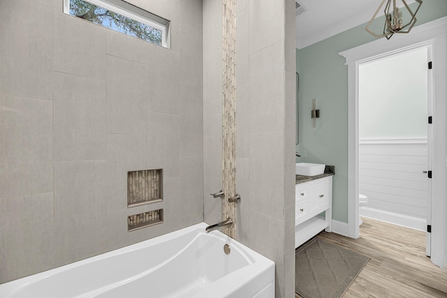 full bath featuring vanity, wood finished floors, baseboards,  shower combination, and toilet