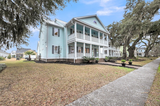 neoclassical home with a front yard, a balcony, a ceiling fan, a porch, and metal roof