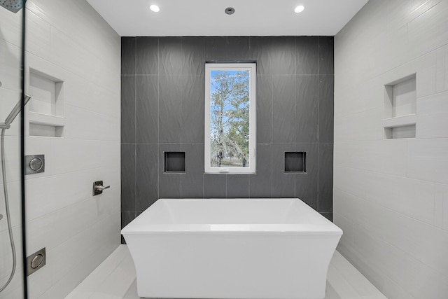 bathroom with recessed lighting, tile walls, and a freestanding tub