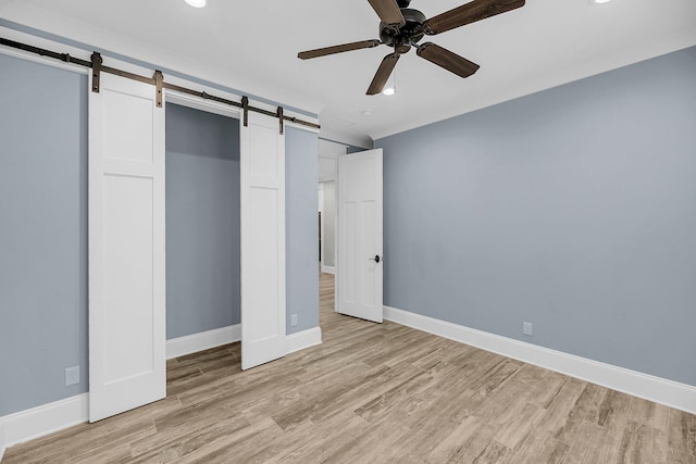 unfurnished bedroom with baseboards, light wood-style floors, and a barn door