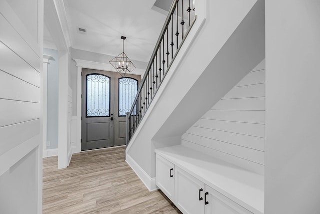 entrance foyer with stairway, visible vents, baseboards, an inviting chandelier, and light wood-style floors