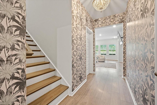 corridor with wallpapered walls, baseboards, stairway, and wood finished floors