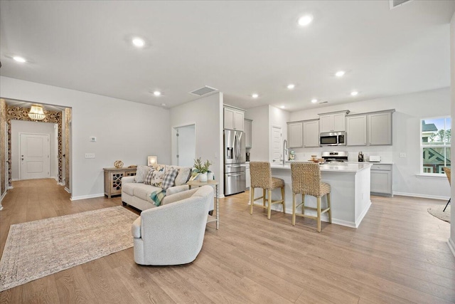 living room with baseboards, recessed lighting, visible vents, and light wood-style floors