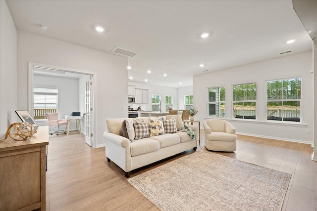 living room with light wood-type flooring, baseboards, visible vents, and recessed lighting