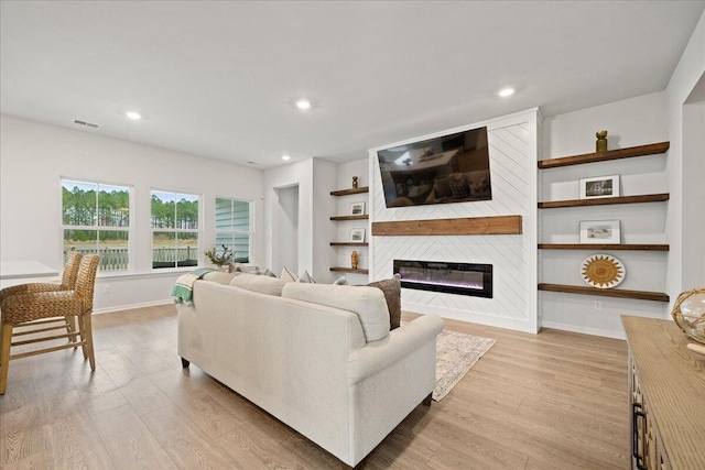 living area with a glass covered fireplace, light wood-style flooring, baseboards, and recessed lighting