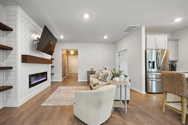 living area featuring a fireplace, visible vents, wood finished floors, and recessed lighting