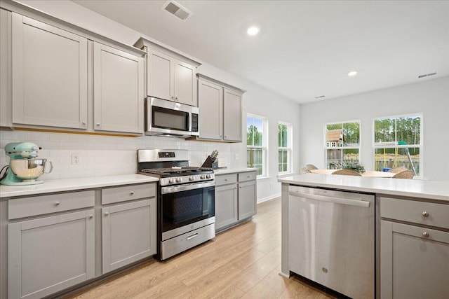 kitchen with appliances with stainless steel finishes, gray cabinets, and decorative backsplash