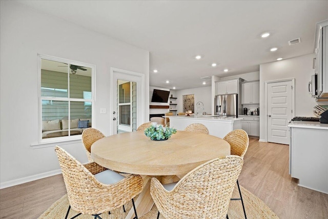 dining space with baseboards, light wood finished floors, visible vents, and recessed lighting