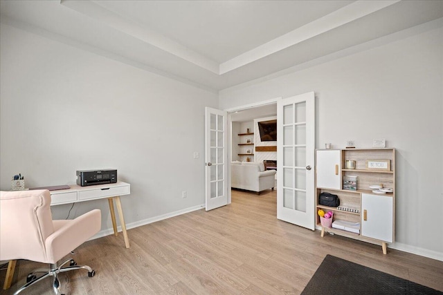 office area with a tray ceiling, french doors, baseboards, and wood finished floors