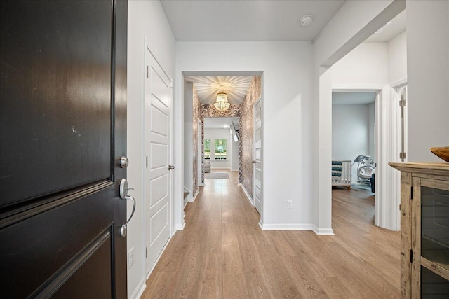 hall featuring light wood-style floors and baseboards