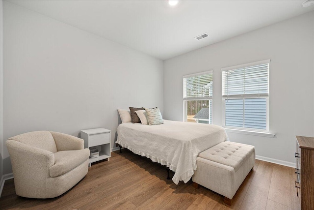 bedroom with wood finished floors, visible vents, and baseboards