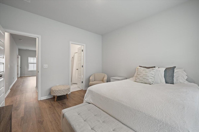 bedroom featuring ensuite bathroom, baseboards, and wood finished floors