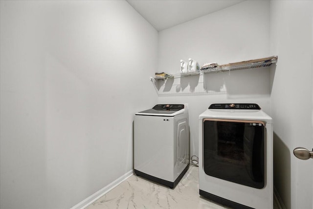 clothes washing area featuring laundry area, independent washer and dryer, marble finish floor, and baseboards