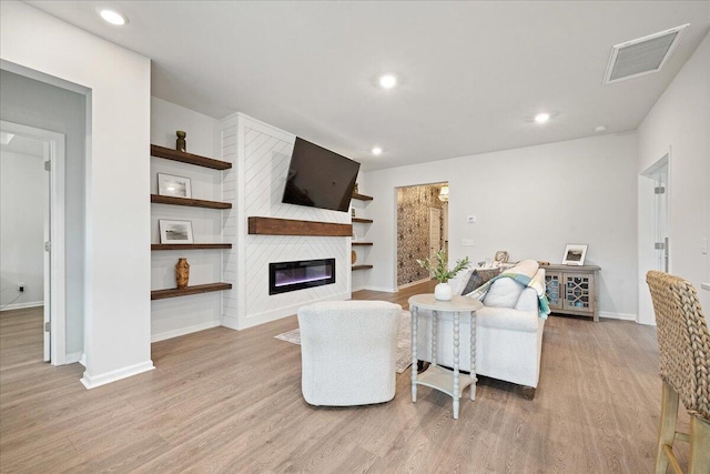 living area with recessed lighting, a large fireplace, wood finished floors, visible vents, and baseboards