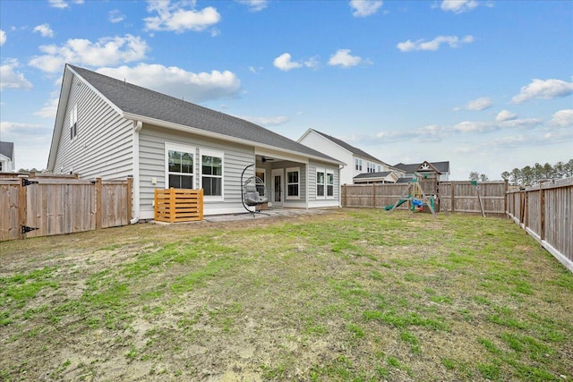 rear view of property with a ceiling fan, a patio, a fenced backyard, a yard, and a playground