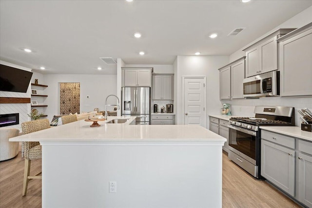 kitchen featuring open floor plan, appliances with stainless steel finishes, light wood finished floors, and gray cabinets