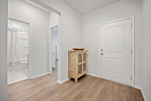 foyer entrance with light wood-style flooring and baseboards