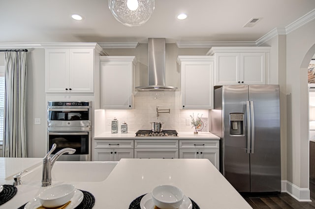 kitchen with white cabinets, dark hardwood / wood-style floors, wall chimney range hood, and appliances with stainless steel finishes