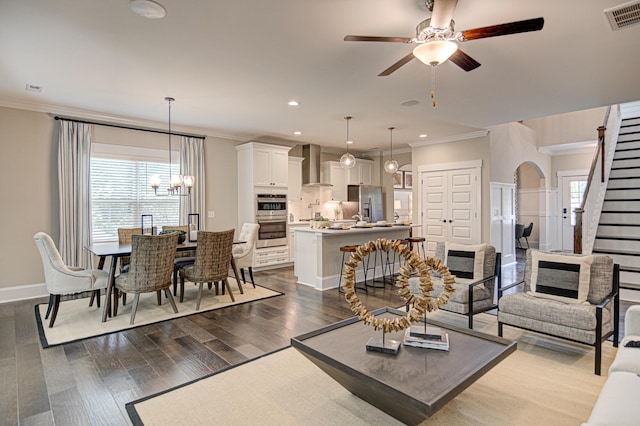 living room featuring ceiling fan with notable chandelier, dark hardwood / wood-style flooring, and ornamental molding