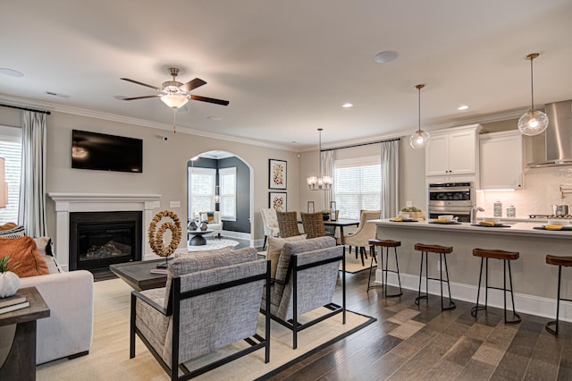 living room with hardwood / wood-style floors, ceiling fan with notable chandelier, and ornamental molding