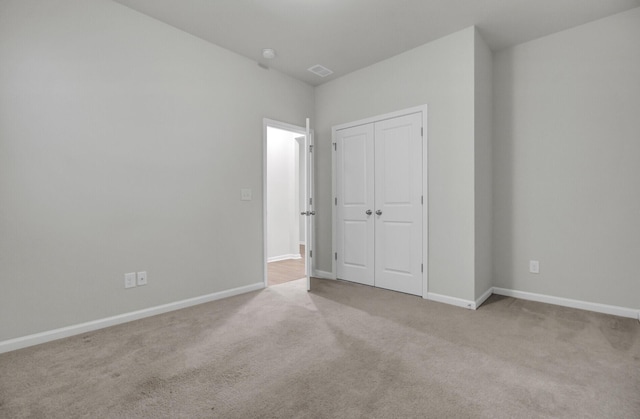 unfurnished bedroom featuring light colored carpet and a closet