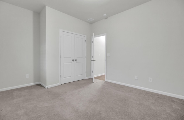 unfurnished bedroom featuring light colored carpet and a closet