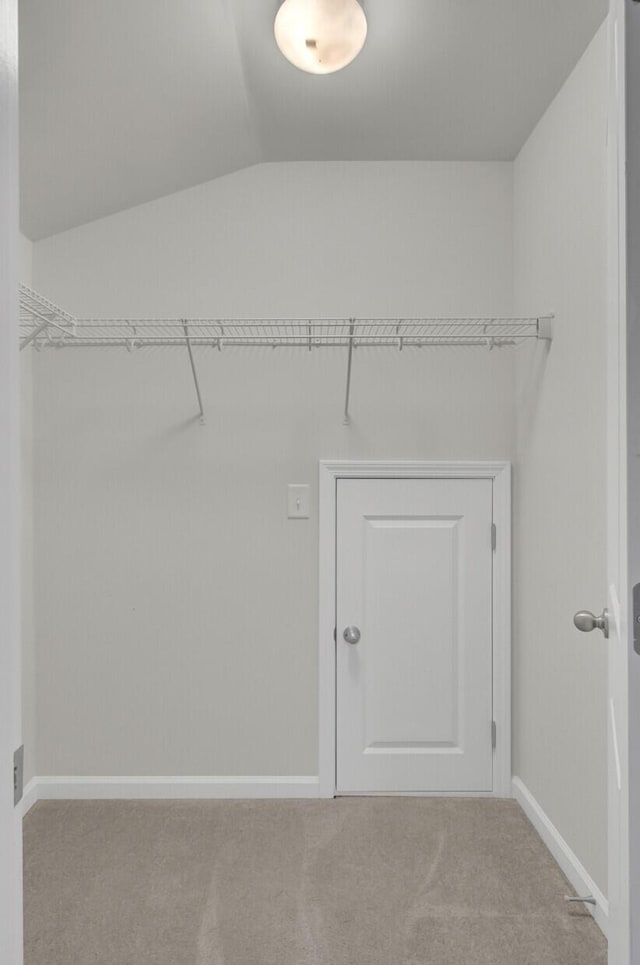 walk in closet with light colored carpet and lofted ceiling