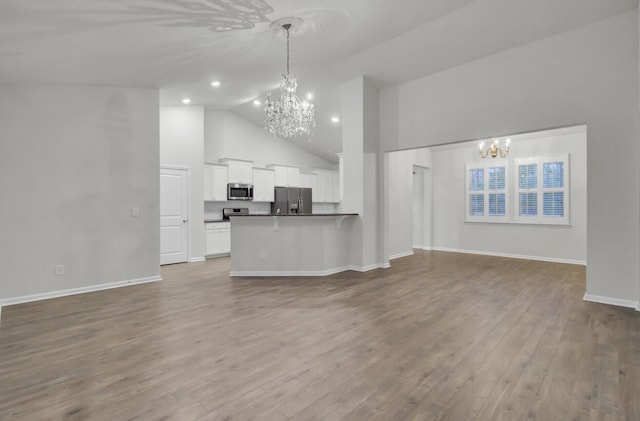 unfurnished living room with wood-type flooring, a chandelier, and high vaulted ceiling