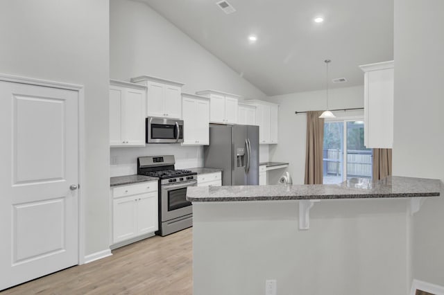 kitchen featuring white cabinetry, stainless steel appliances, kitchen peninsula, and a kitchen bar